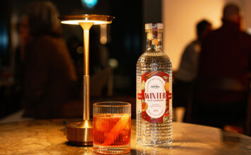 Eden Mill unveils Winter gin for Negroni cocktails A bottle of Eden Mill Winter in St Andrews gin stands on a table with a Negroni cocktail serve next to it and a lamp.