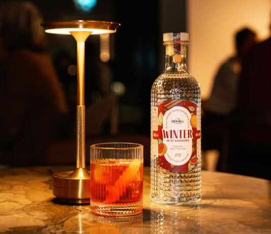 Eden Mill unveils Winter gin for Negroni cocktails A bottle of Eden Mill Winter in St Andrews gin stands on a table with a Negroni cocktail serve next to it and a lamp.