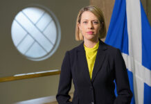 Industry calls on ScotGov to act before rates soar out of control Jenny Gilruth, deputy First Minister of the Scottish Government, stands in Parliament with the Scotland flag behind her.