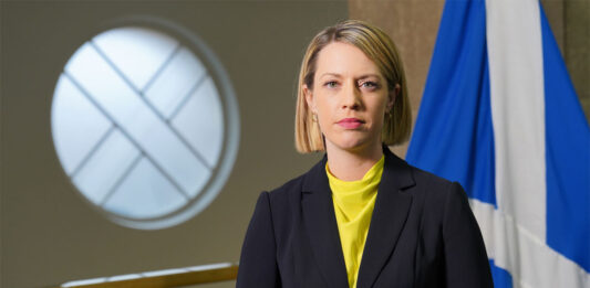Industry calls on ScotGov to act before rates soar out of control Jenny Gilruth, deputy First Minister of the Scottish Government, stands in Parliament with the Scotland flag behind her.