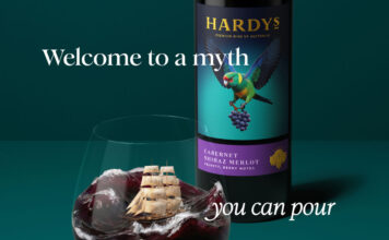 Hardys wine unveils complete brand refresh Promotional image of the new Hardys wine redesign with a bottle of the wine in the background with a glass of red wine poured in front of it. The wine inside mimics a stormy sea with a ship in the tides. The text around the two reads 'Welcome to a myth you can pour'.