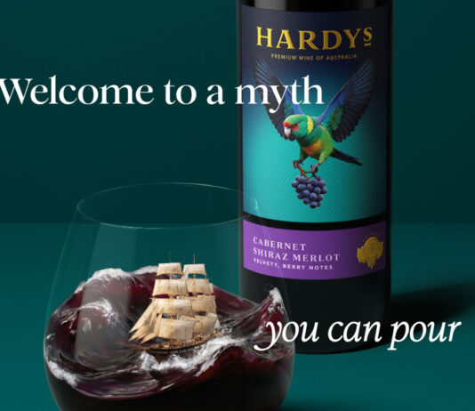Hardys wine unveils complete brand refresh Promotional image of the new Hardys wine redesign with a bottle of the wine in the background with a glass of red wine poured in front of it. The wine inside mimics a stormy sea with a ship in the tides. The text around the two reads 'Welcome to a myth you can pour'.