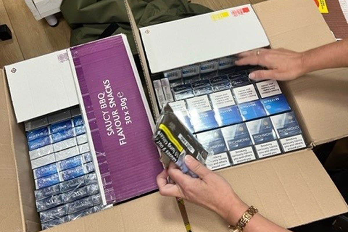 Boxes filled with illicit cigarettes as a person examines the contents inside.