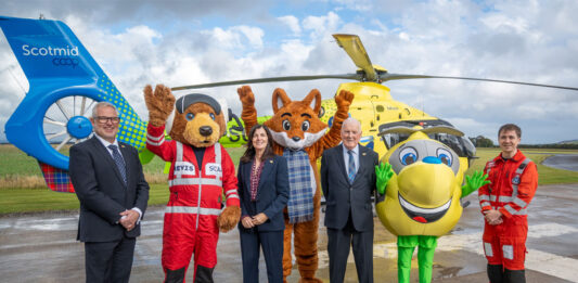 Scotmid partnership with Air Ambulance takes off Scotmid Co-op representatives and members of Scotland's Charity Air Ambulance stand on a heliport with their respective mascots and a helicopter behind them.
