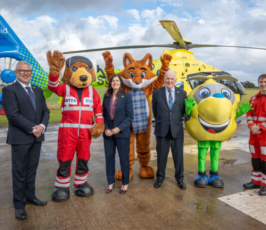 Scotmid partnership with Air Ambulance takes off Scotmid Co-op representatives and members of Scotland's Charity Air Ambulance stand on a heliport with their respective mascots and a helicopter behind them.