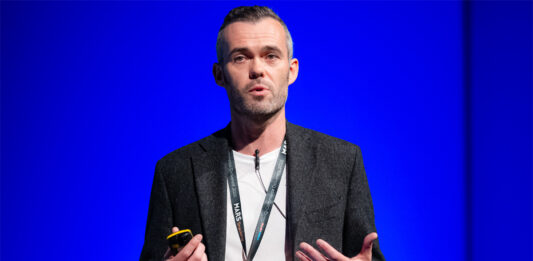 Snappy Group receives seven figure investment from Virgin Money Barry McGonagle, chief financial officer at Snappy Group, stands on a stage with a blue backdrop delivering a talk.