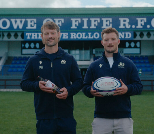The Famous Grouse backs grassroots rugby with competition Members of the Howe of Fife RFC team stand on a rugby pitch holding a rugby ball as well as a bottle of The Famous Grouse.