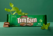 Tim Tam Mint hits Waitrose store shelves A pack of Arnott's Tim Tam Mint sits on a green table against a green background with mint sprigs around the pack.